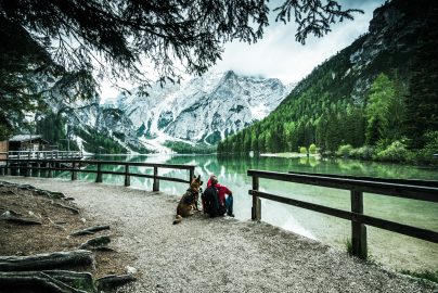 Active man and dog looking at Pragser Wildsee or Braies Lake