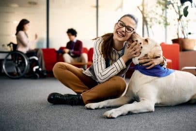 Happy businesswoman enjoying with therapy dog in the office.