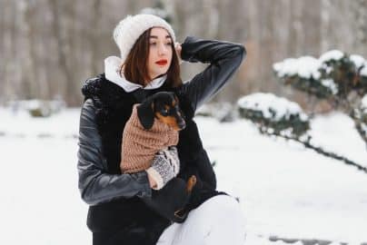 The girl walks with a dog in the winter.