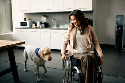 Therapy dog and businesswoman with a disability in the kitchen at corporate office.